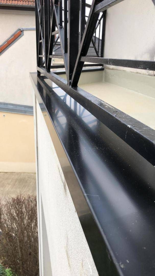 Garde-corps de fenêtre en métal noir et mur extérieur vus depuis un balcon ou une cage d’escalier.