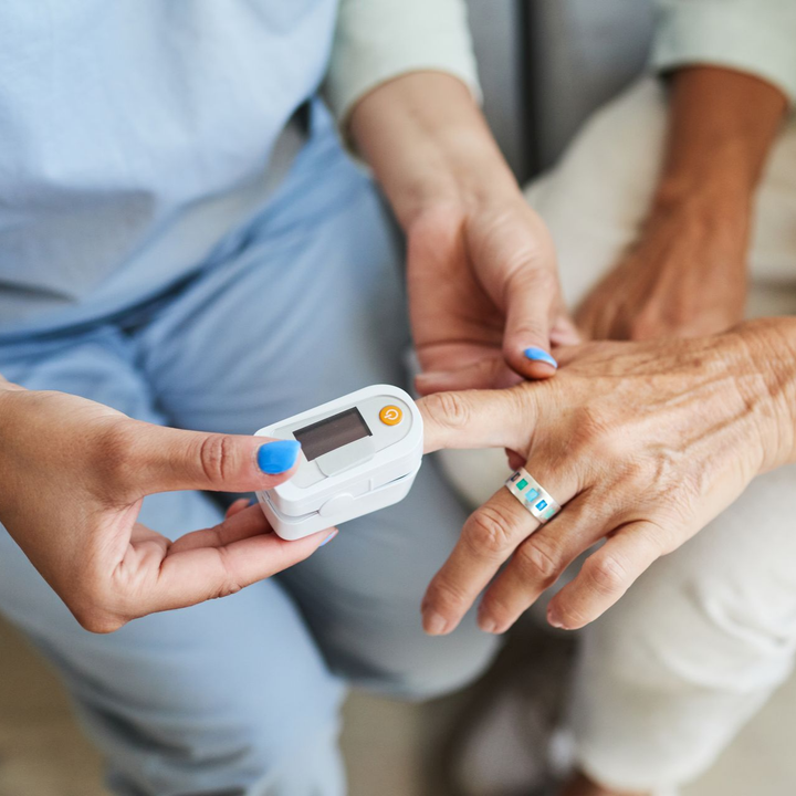 Un professionnel de la santé utilise un oxymètre de pouls sur le doigt d'une personne âgée pour mesurer la saturation en oxygène.