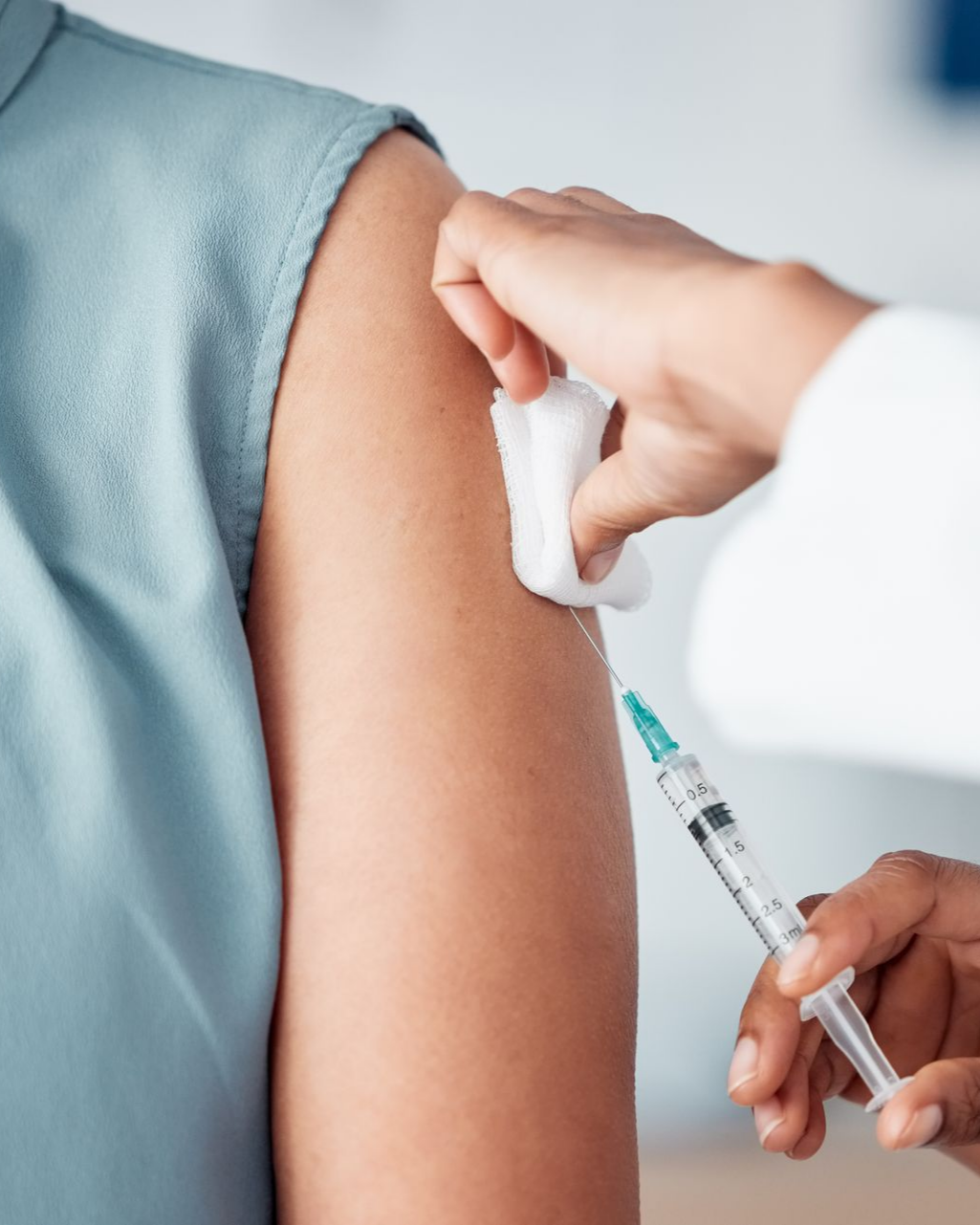 Personne recevant un vaccin dans la partie supérieure du bras ; professionnel de la santé administrant l'injection.