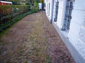 Lagenweise verdichtete Erdreichwiederverfüllung am sanierten Kelleraußenmauerwerk.