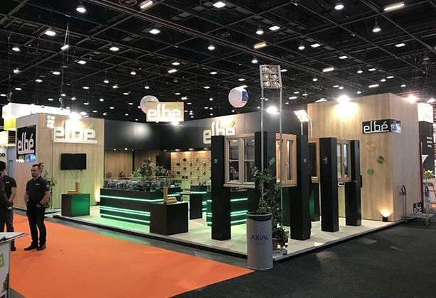 Un stand d'exposition avec des murs lambrissés, des vitrines et des touches d'éclairage vert.
