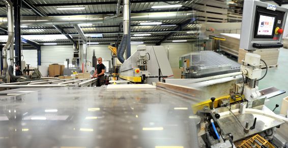 Un ouvrier surveille des machines à bois automatisées dans une grande usine industrielle.
