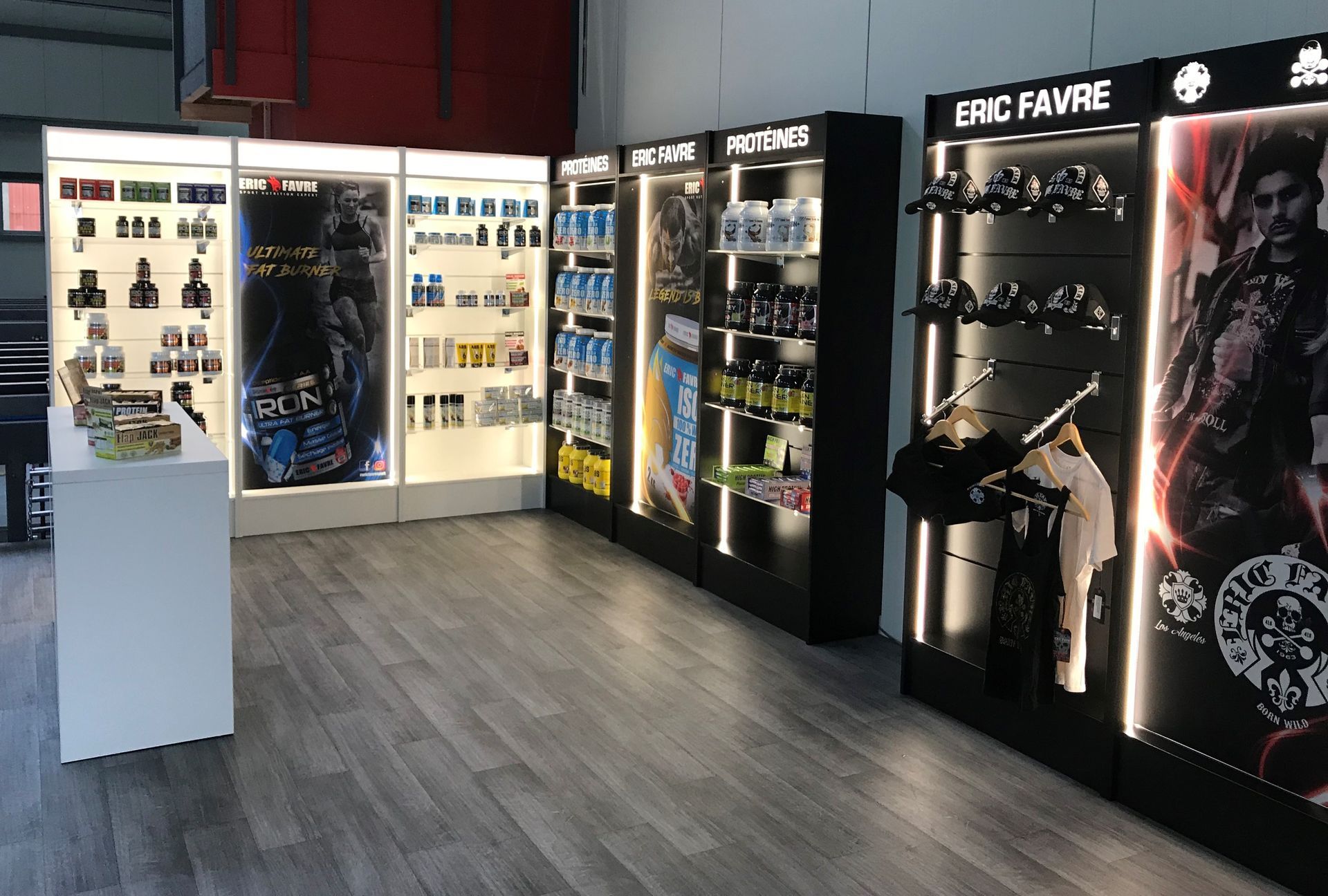 Intérieur d'un magasin présentant des rangées d'étagères lumineuses remplies de compléments alimentaires pour le fitness et la musculation.