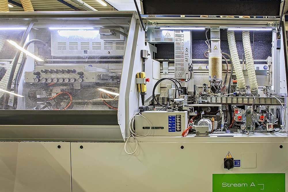 Vue industrielle grand angle d'une machine de production automatisée blanche et fermée, avec des composants mécaniques internes.