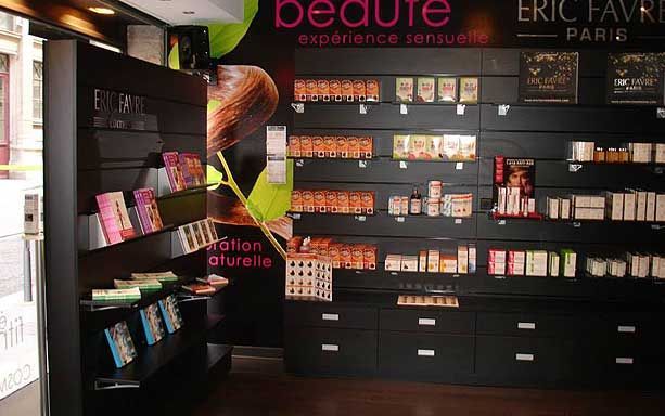 Un présentoir de rayon avec des panneaux muraux noirs présentant divers produits de beauté et de bien-être Eric Favre disposés en rangées.