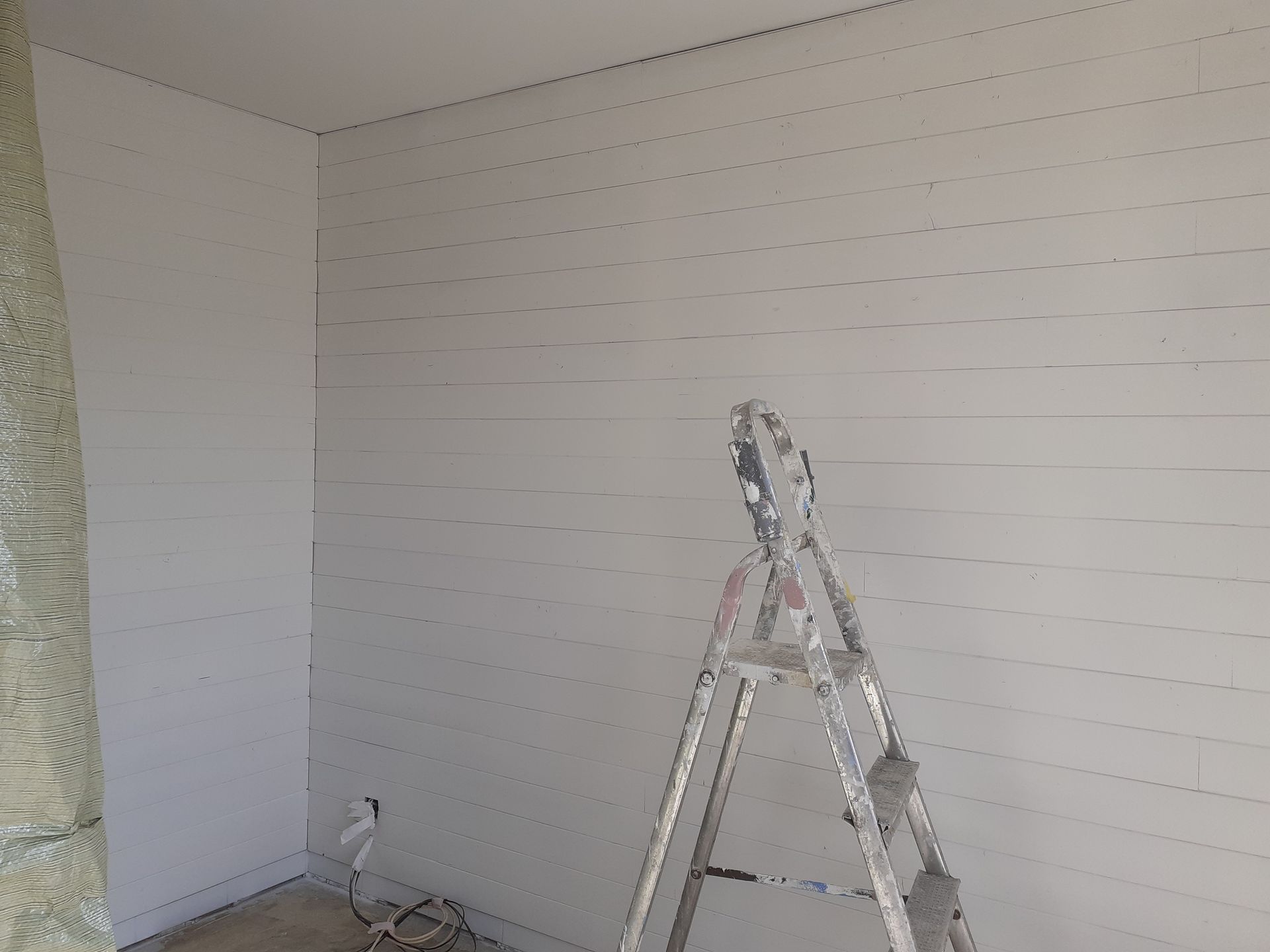 Escabeau posé devant un mur en lambris peint en blanc