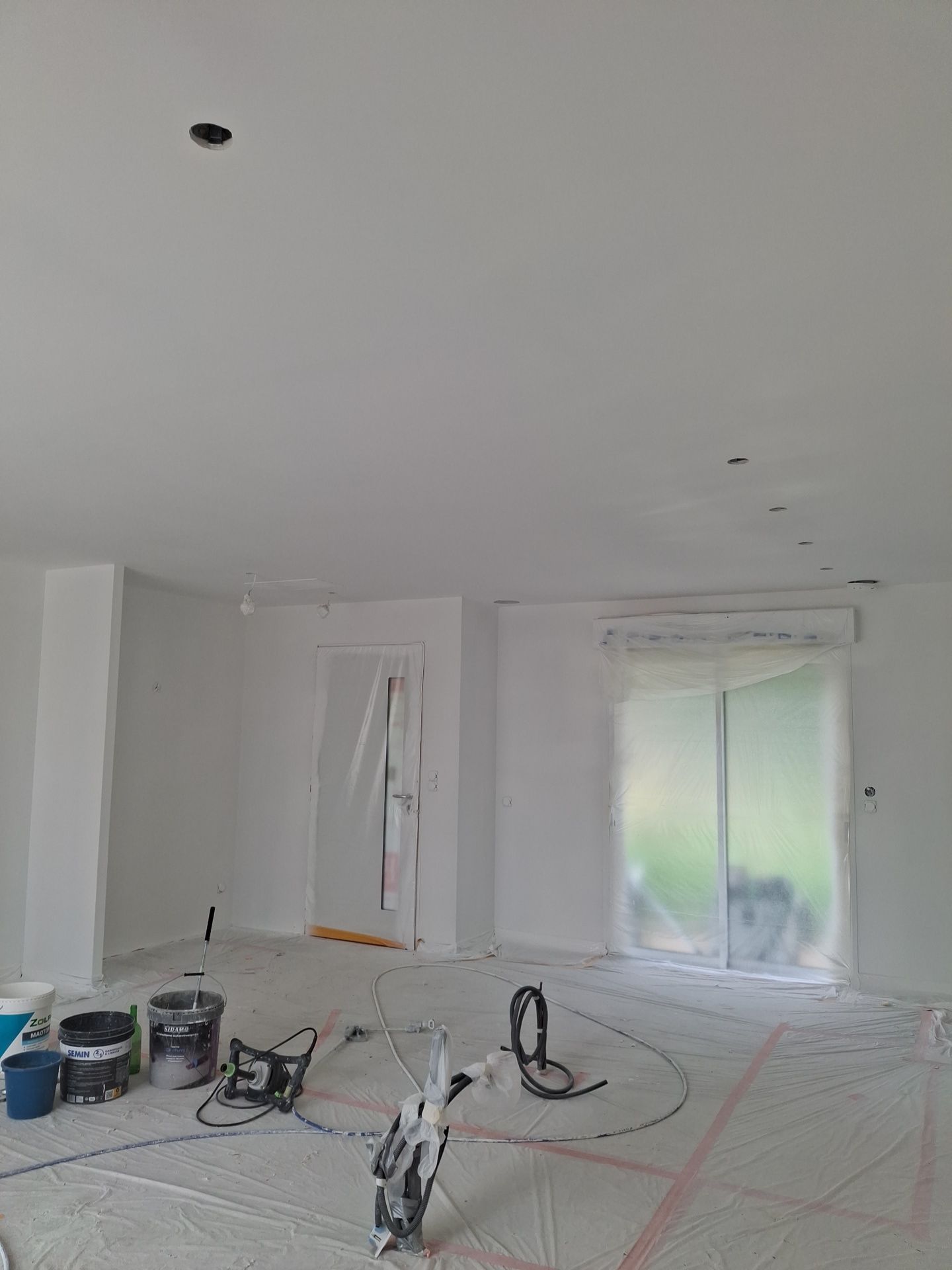 Matériel de peinture Airless posé dans la pièce de vie d'une maison en construction