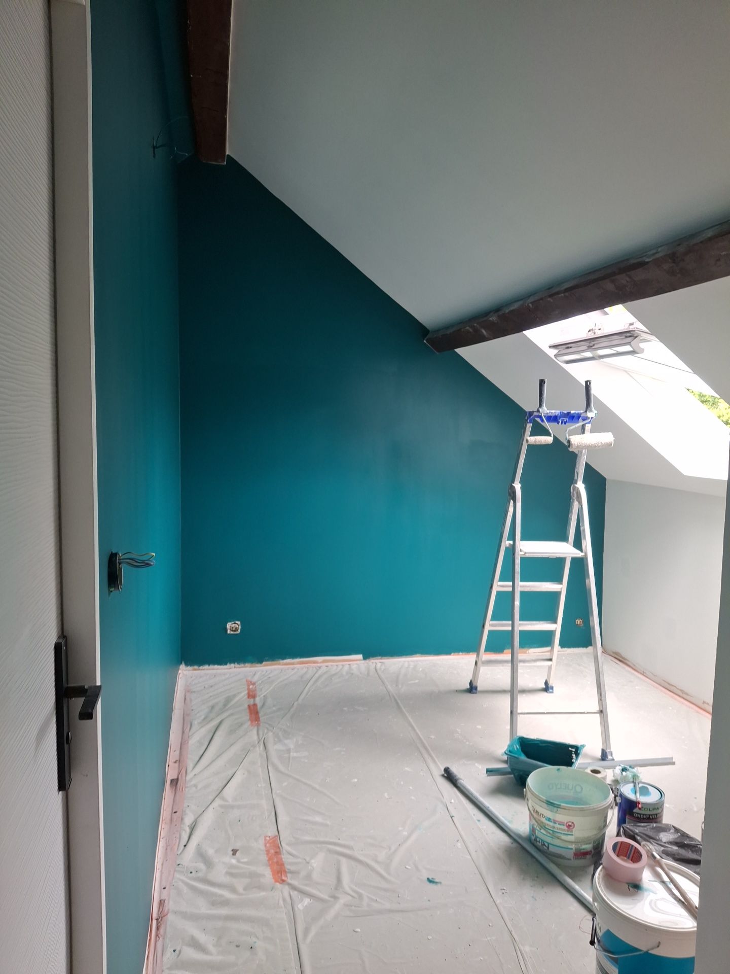 Peinture du mur d'une pièce mansardée en bleu canard