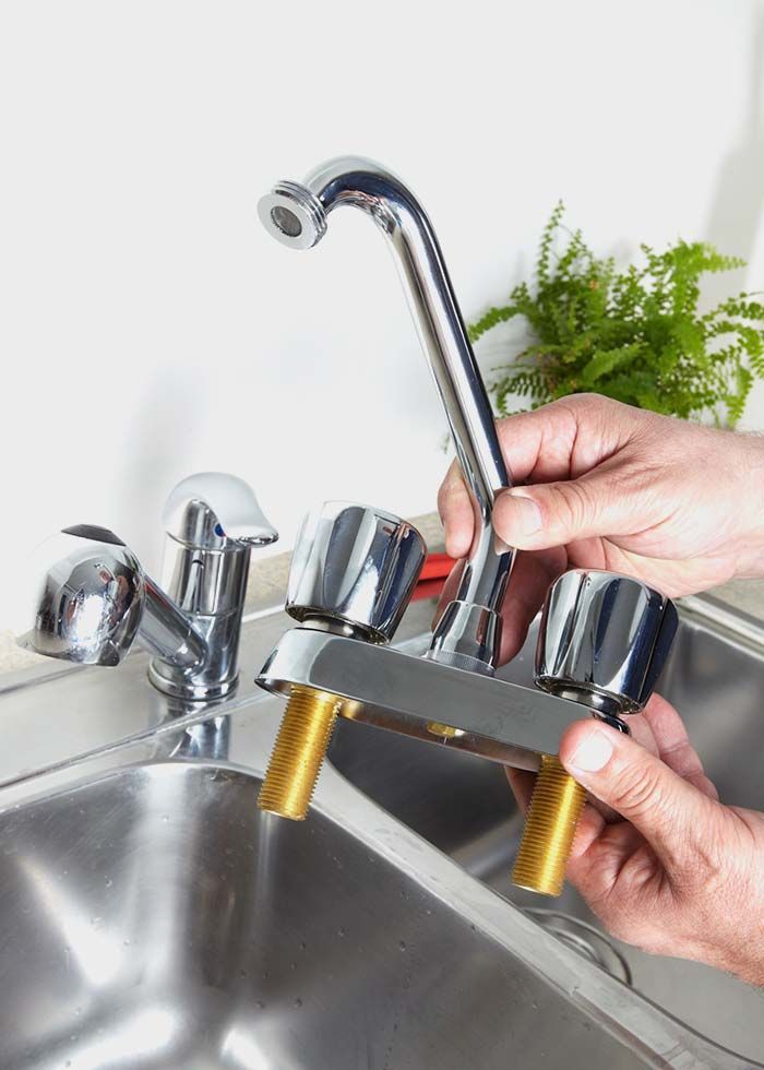 Una persona está arreglando un grifo en un fregadero de cocina.