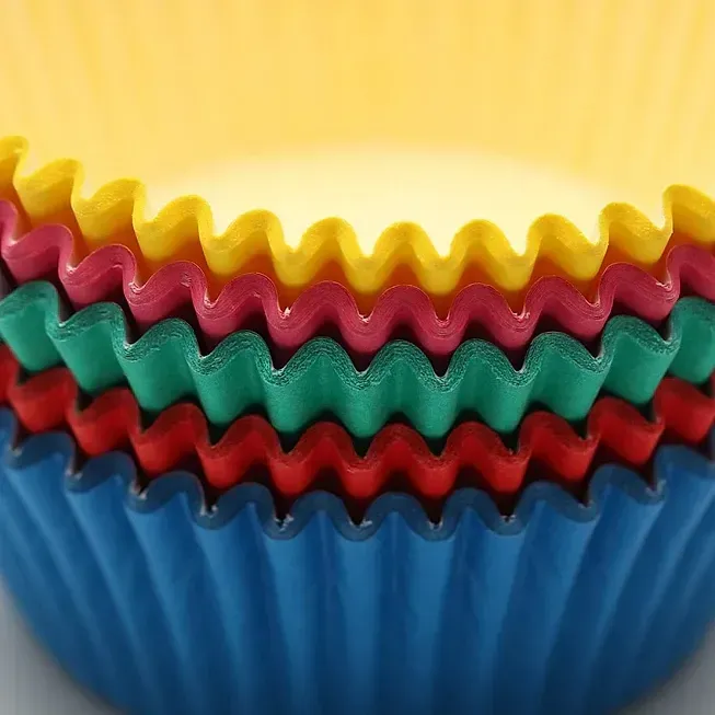 Un primer plano de una pila de envoltorios de cupcakes de colores.