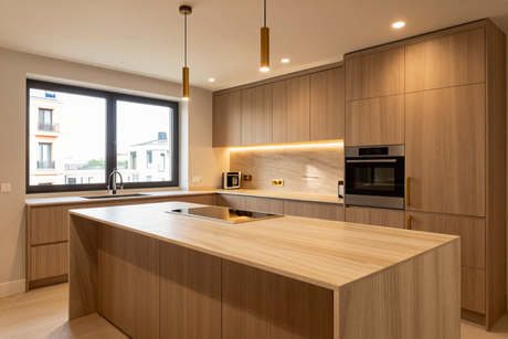 Cocina moderna de madera con una isla grande, horno empotrado y vistas desde la ventana.