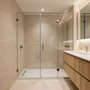 Baño moderno en tonos beige, con ducha de cristal, suelo blanco sin bañera y mueble de lavabo de madera junto a un espejo