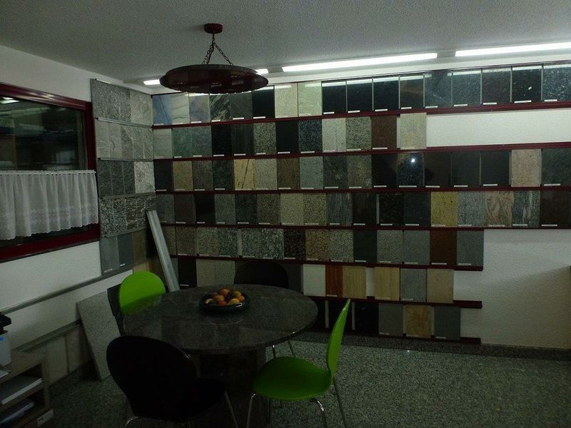 Ein Raum mit einem Tisch und Stühlen vor einer Fliesenwand. Foto von der Hutter Natursteine AG