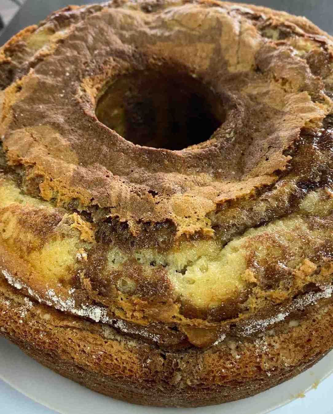 Primer plano de un bizcocho redondo tipo Bundt con una corteza dorada y espolvoreado con azúcar glas.
