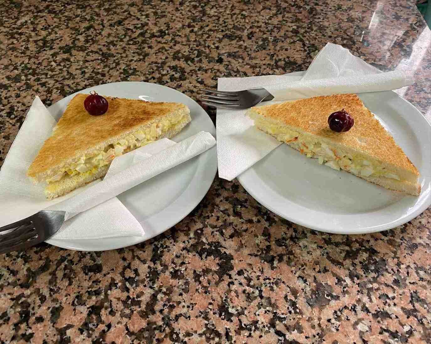 Dos porciones de pastel en platos con servilletas y tenedores sobre una encimera moteada.