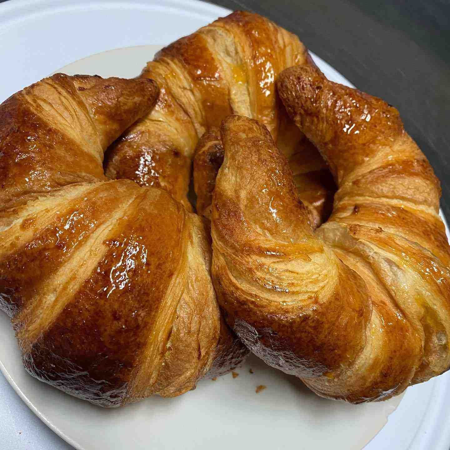 Pastel retorcido glaseado sobre un plato blanco, dorado y hojaldrado.