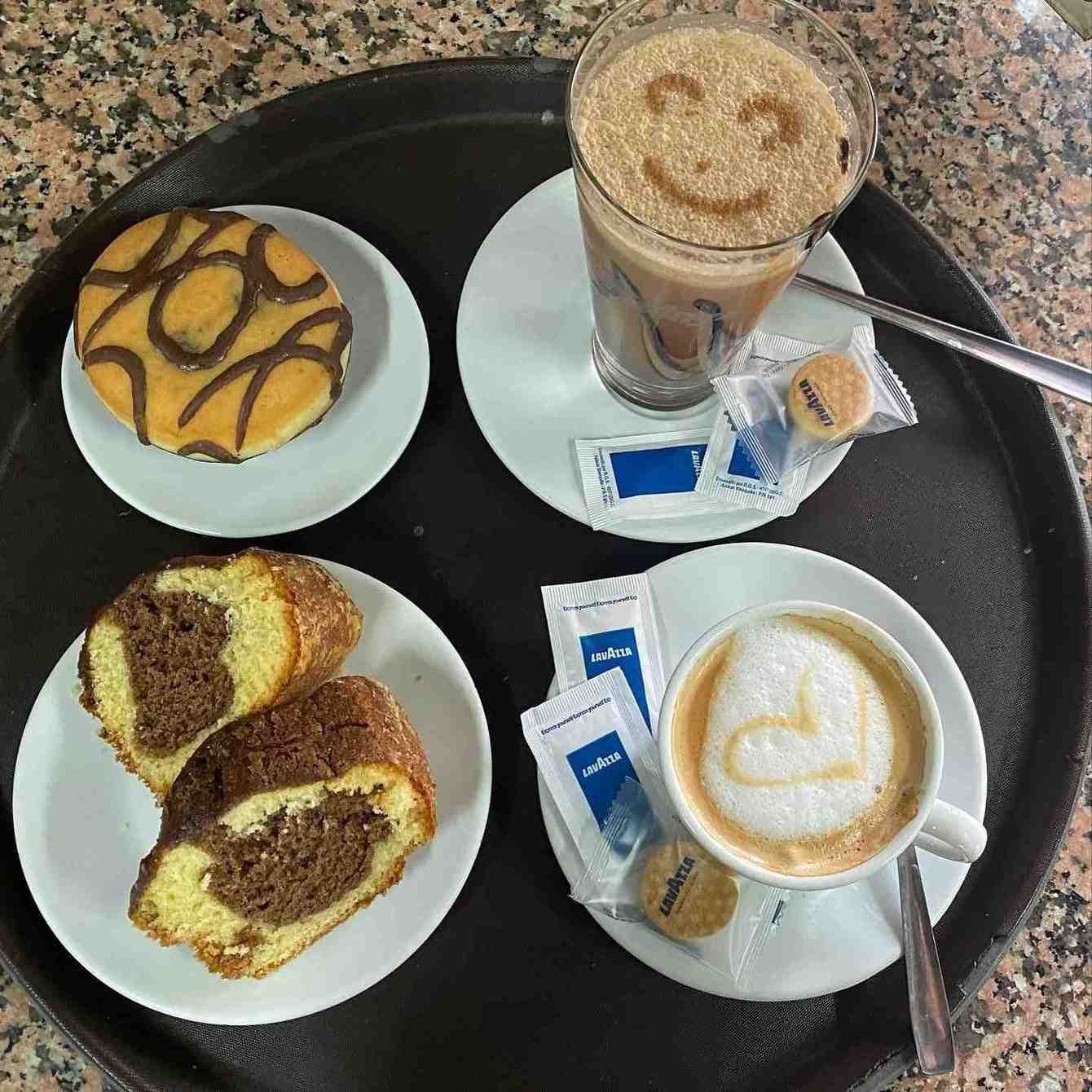 Bandeja con café, pasteles y galletas en platos y tazas pequeñas, vista desde arriba.