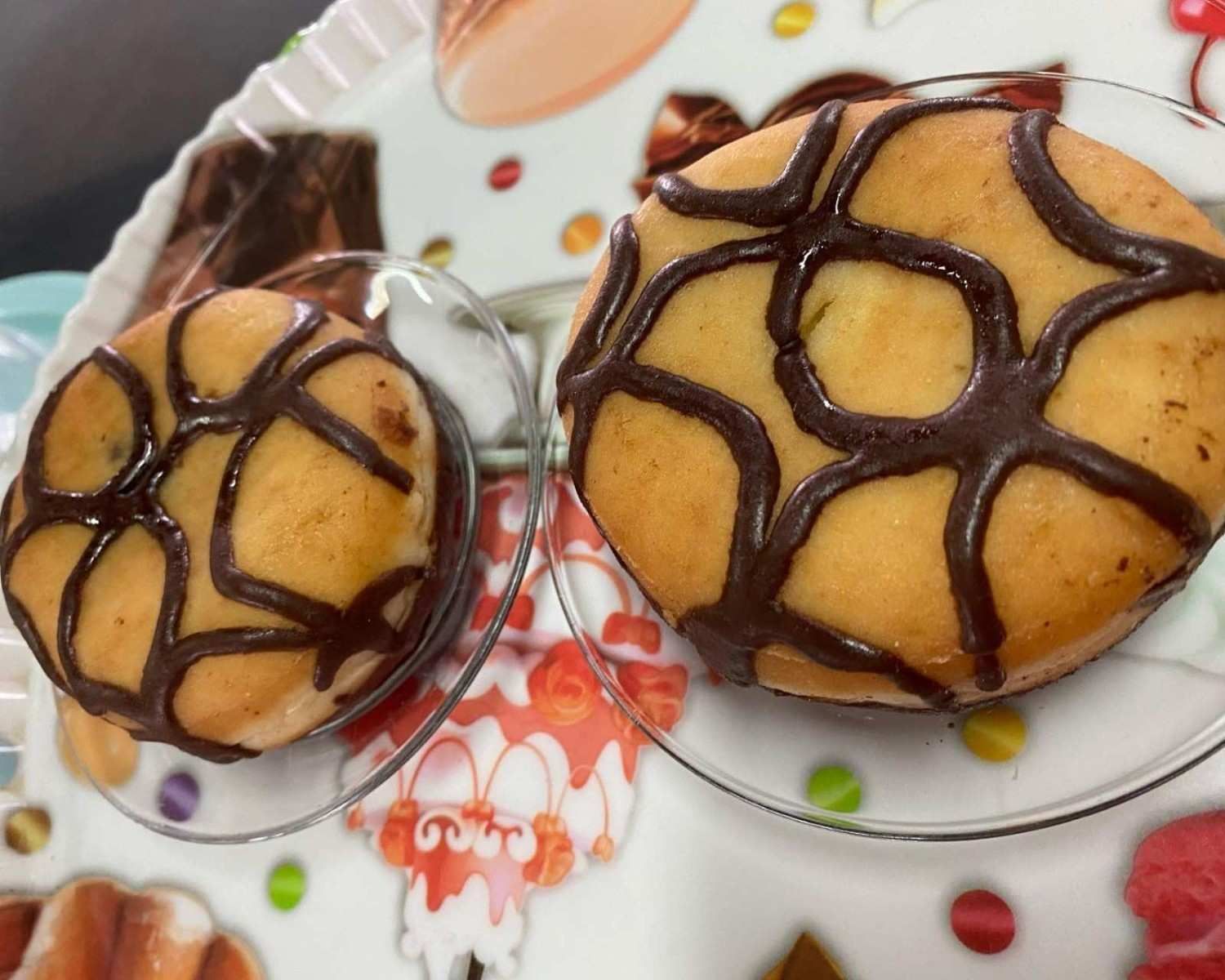 Dos magdalenas bañadas en chocolate sobre un plato estampado.