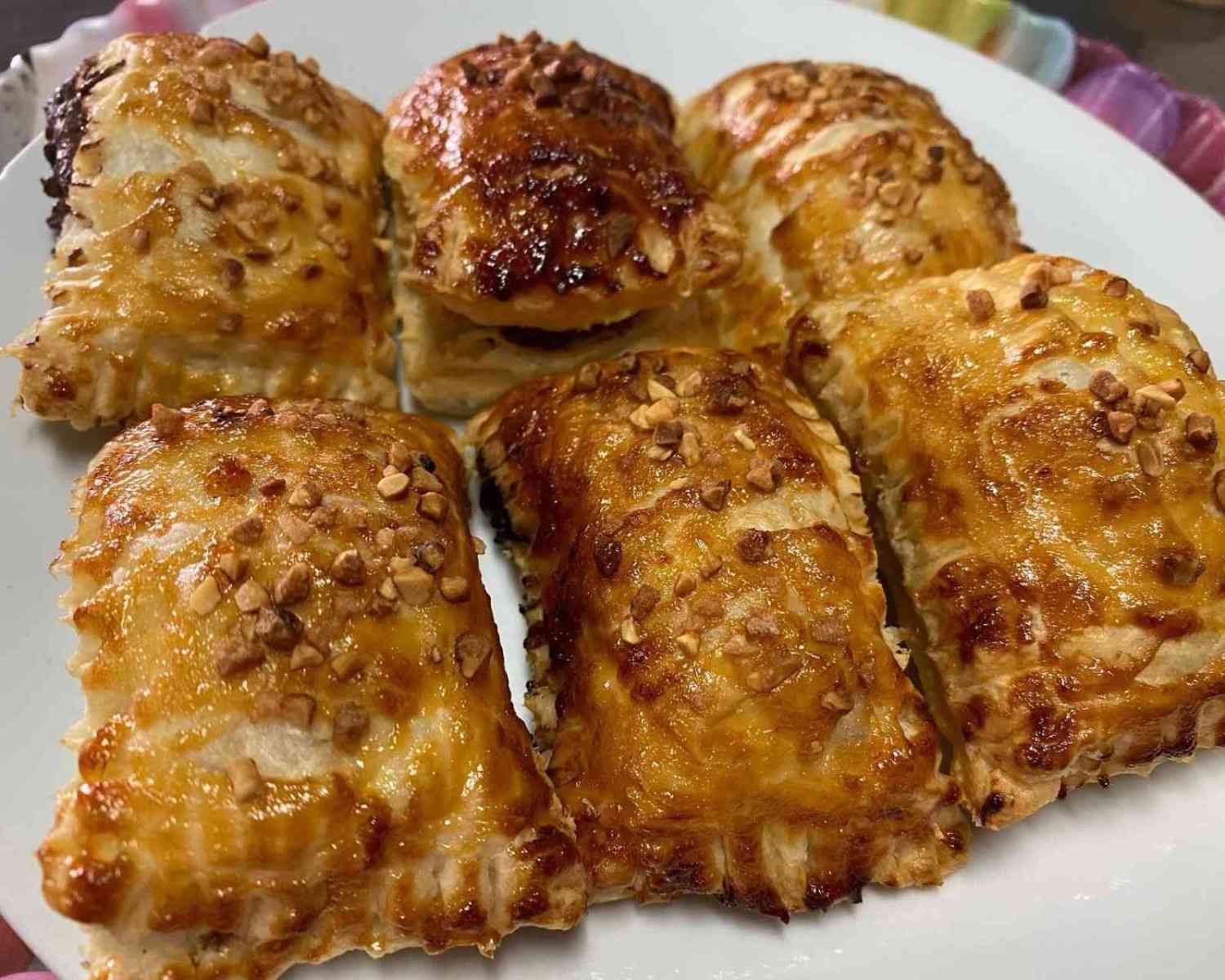 Plato de rollitos de hojaldre glaseados de color marrón dorado con una cobertura crujiente.