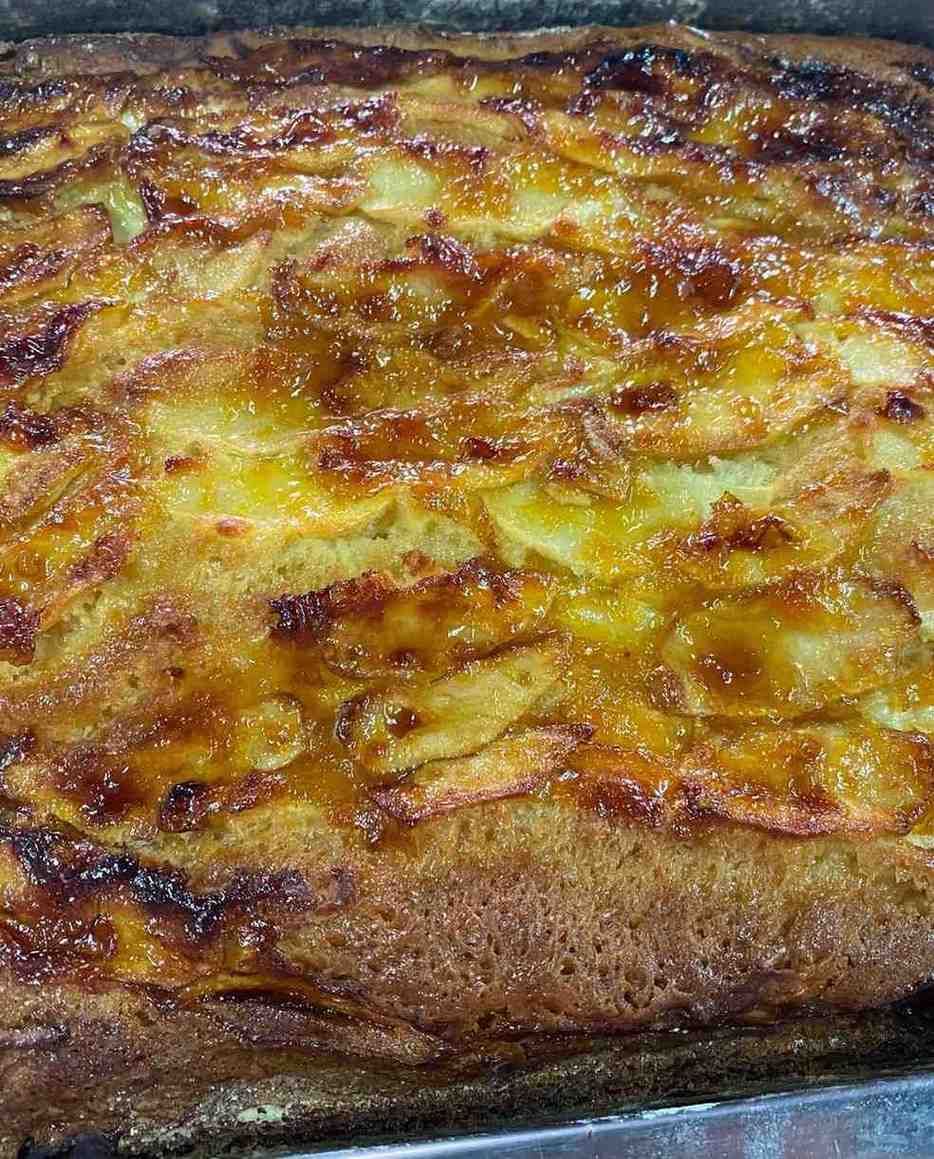 Primer plano de una cazuela horneada de color marrón dorado con una cobertura de queso dorado en una fuente para hornear.