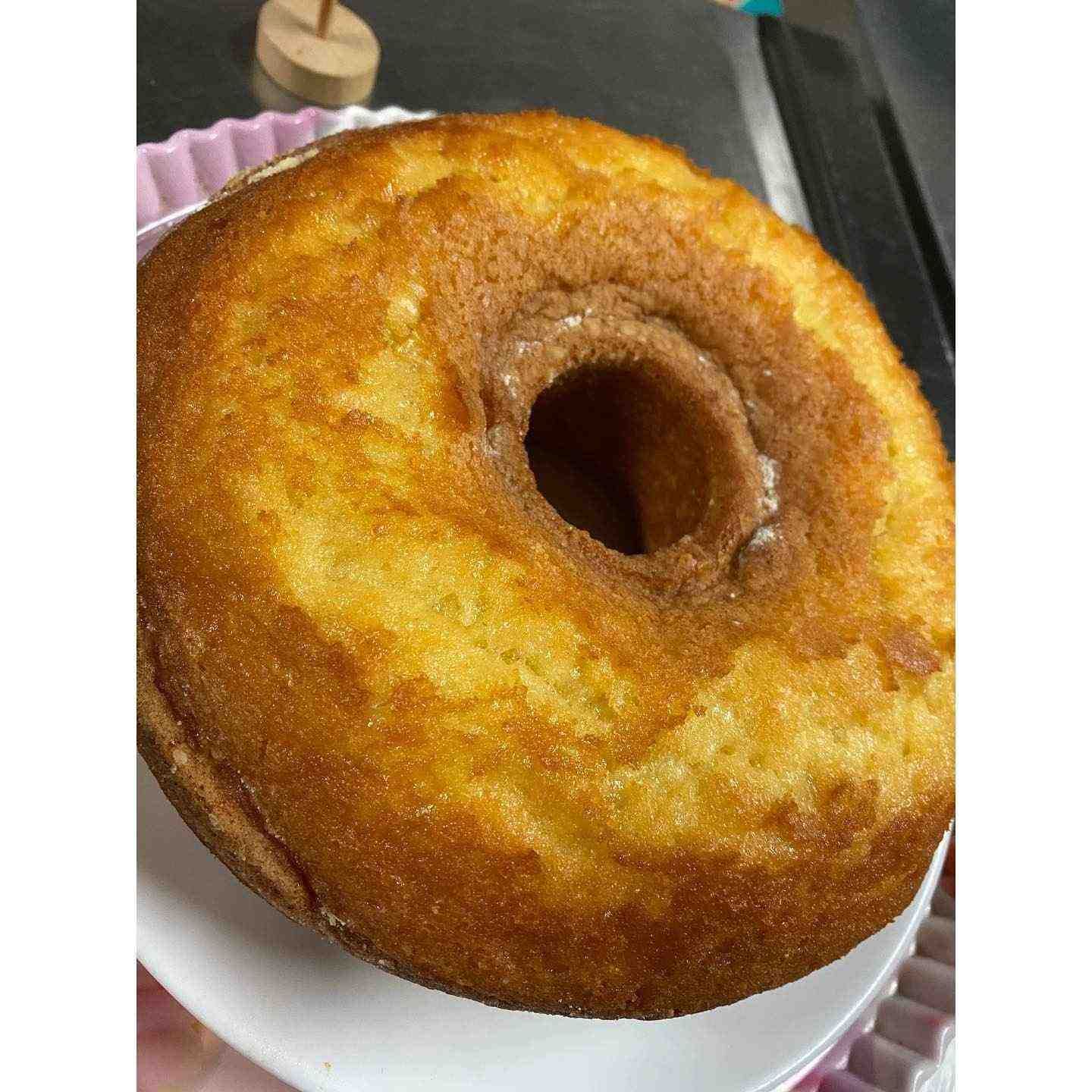 Donut glaseado dorado sobre un plato blanco con borde festoneado rosa.