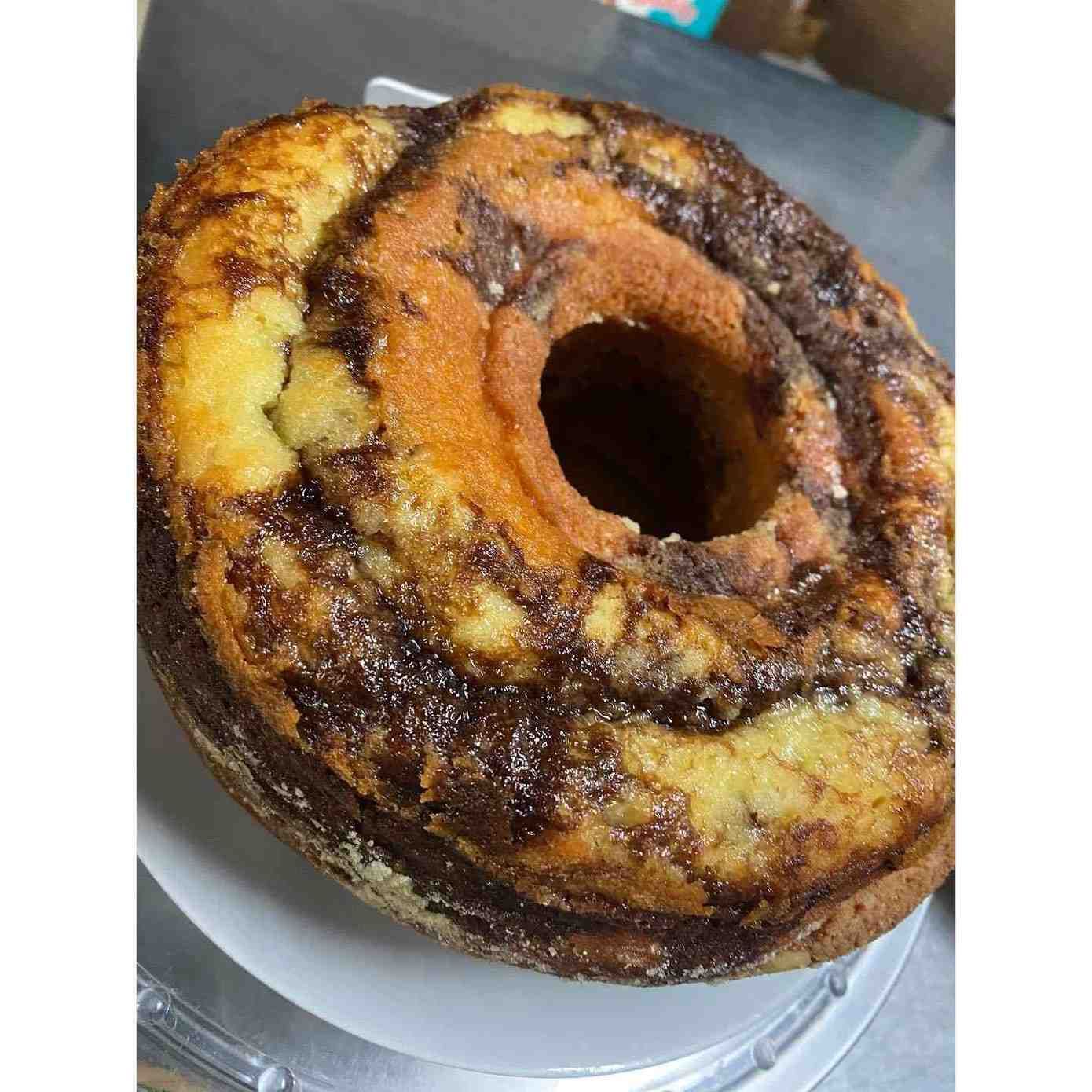 Primer plano de una rosquilla glaseada de chocolate y vainilla sobre un plato transparente.