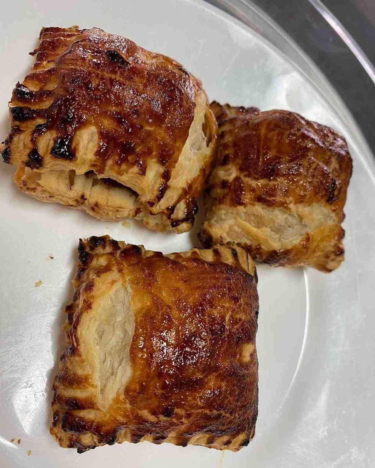 Tres pasteles de hojaldre dorados sobre un plato blanco.