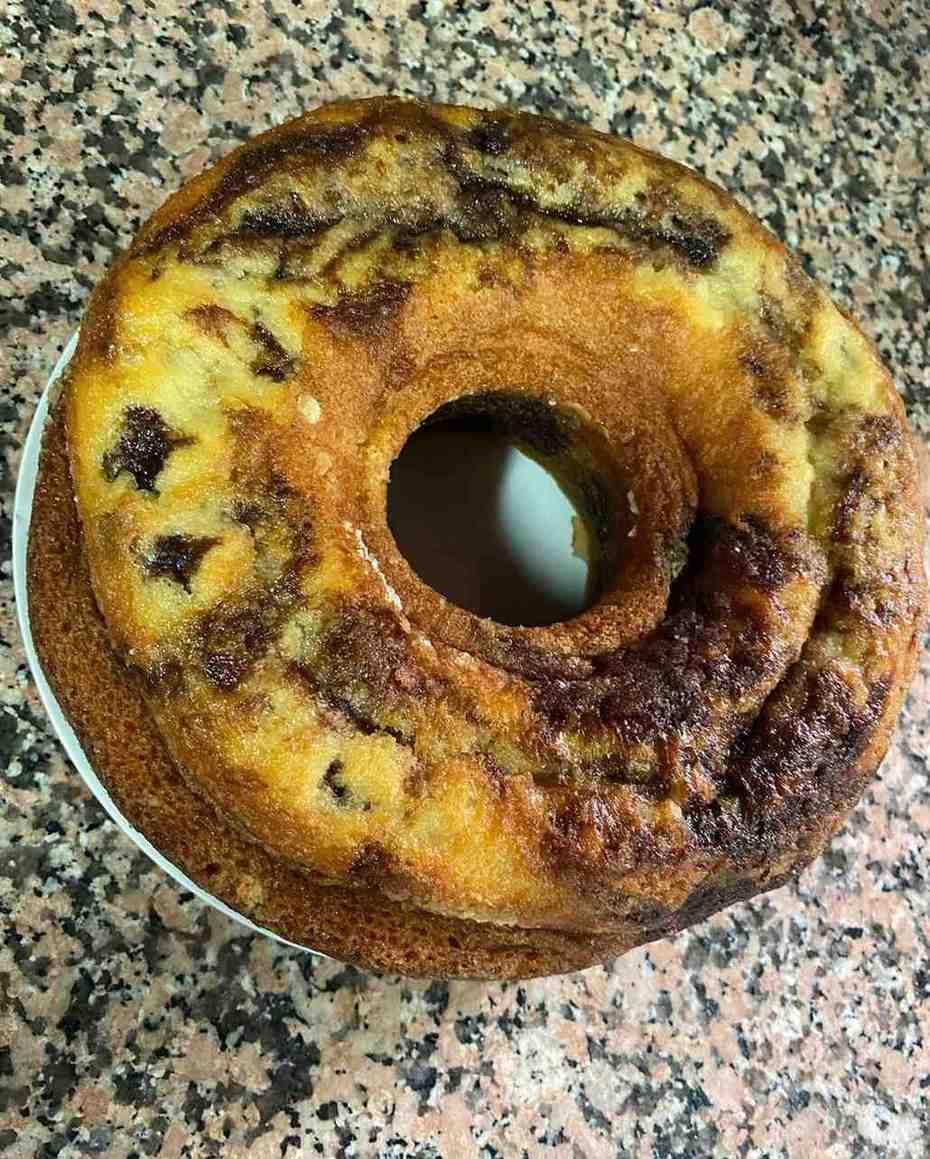 Pastel redondo tostado con un agujero en el centro sobre una encimera moteada.