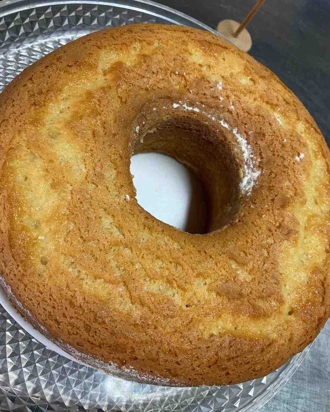 Pastel bundt de color marrón dorado con glaseado brillante sobre un plato estampado.