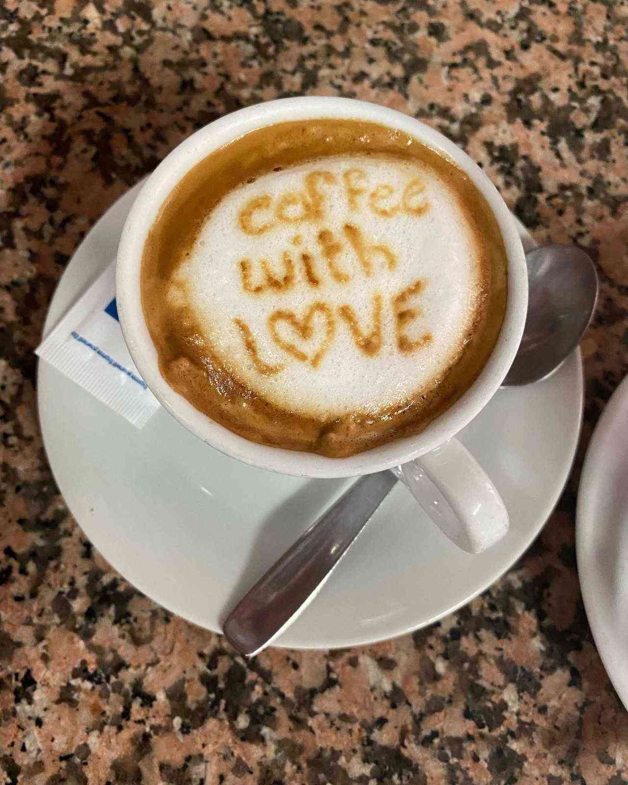Taza de café con dibujo de latte art que dice 