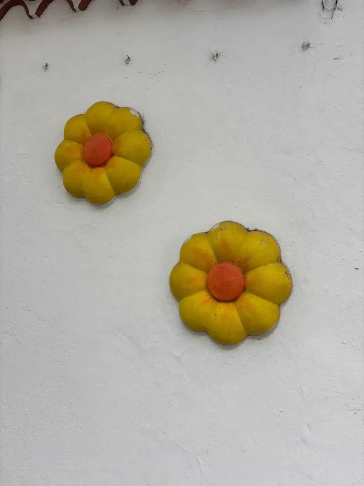 Dos adornos amarillo-anaranjados en forma de flor sobre un fondo blanco.
