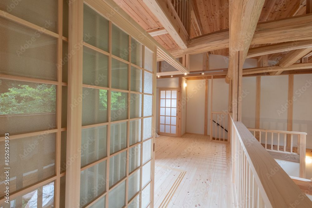 Un couloir en bois avec des portes coulissantes en verre et une balustrade.