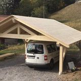 Une camionnette blanche est garée sous un abri en bois.