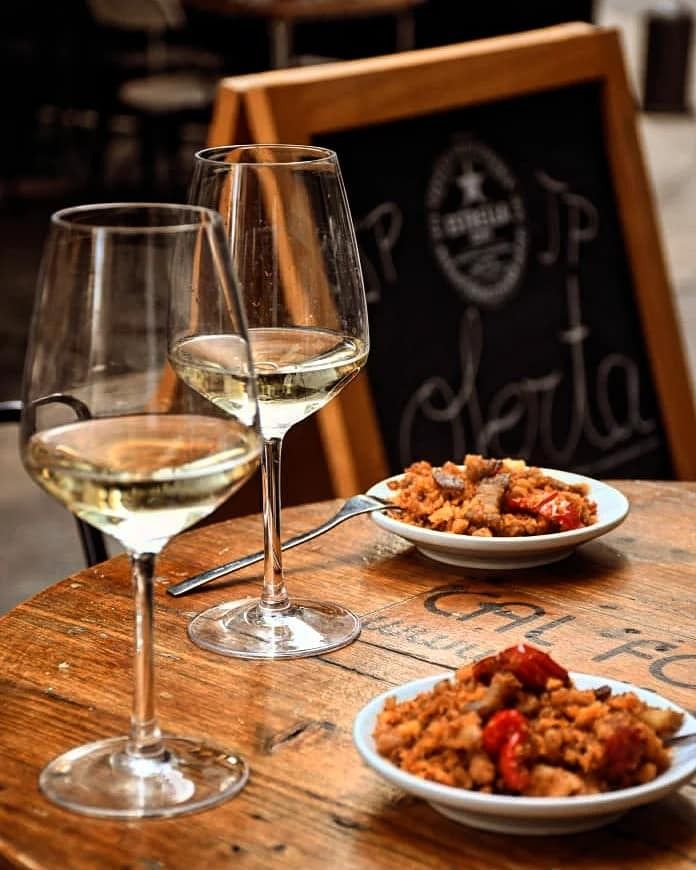 Dos copas de vino y dos platos de comida en una mesa de madera.
