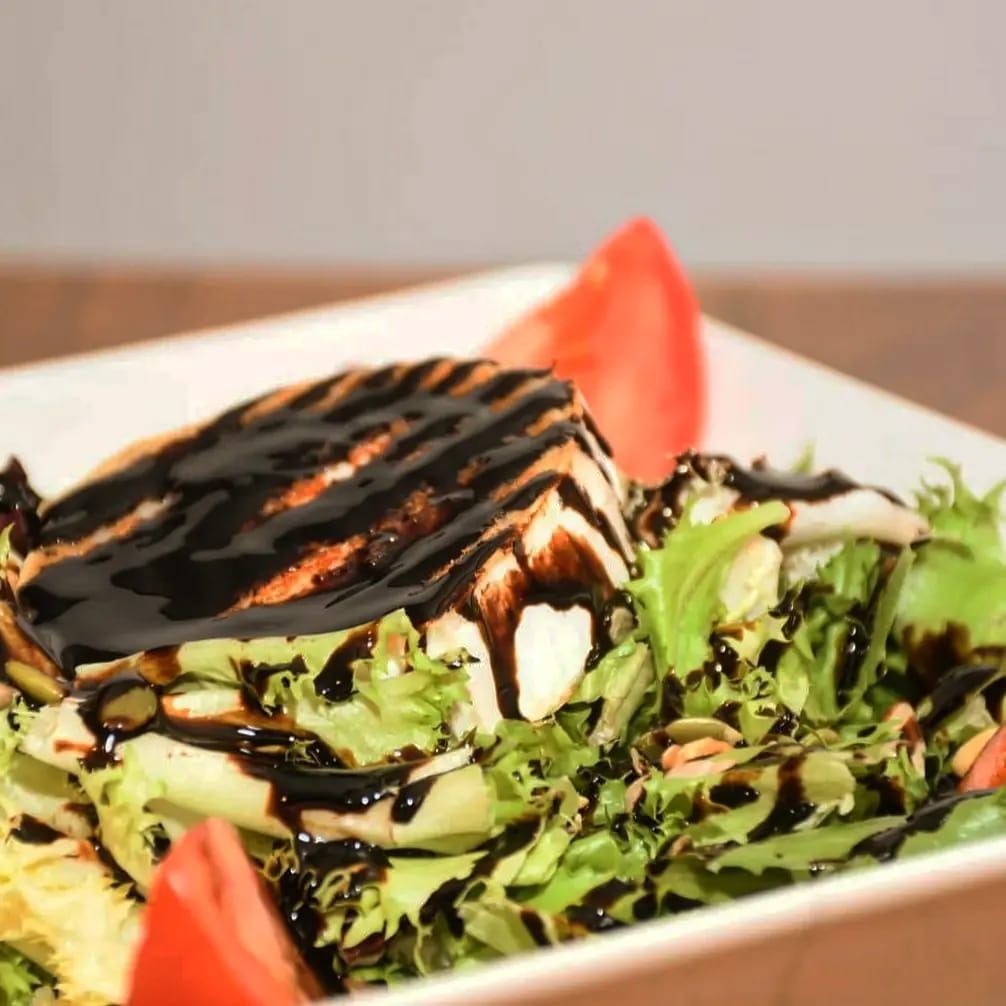 Una ensalada con un trozo de queso a la parrilla encima