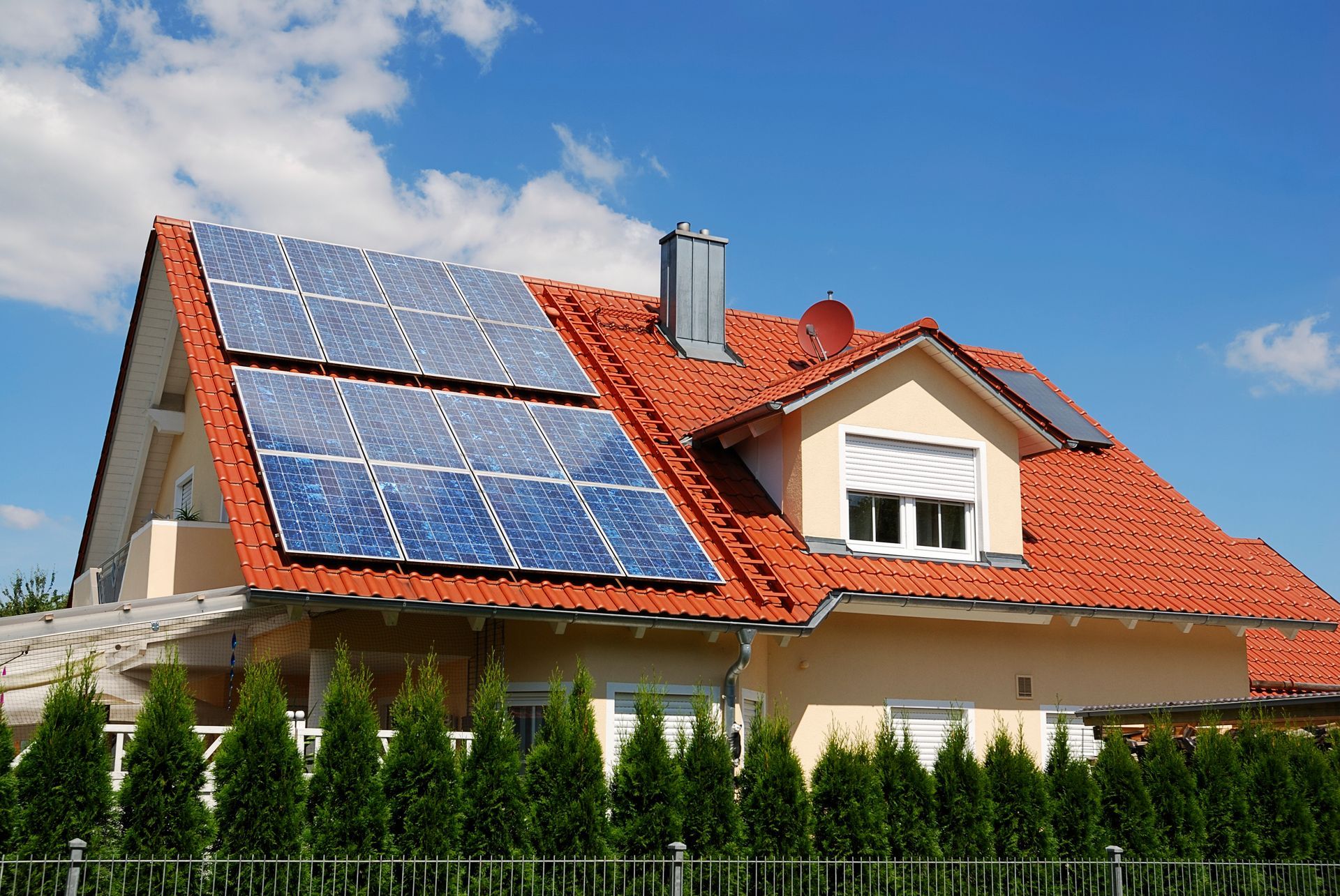 Une maison avec un toit en tuiles et des panneaux photovoltaïques