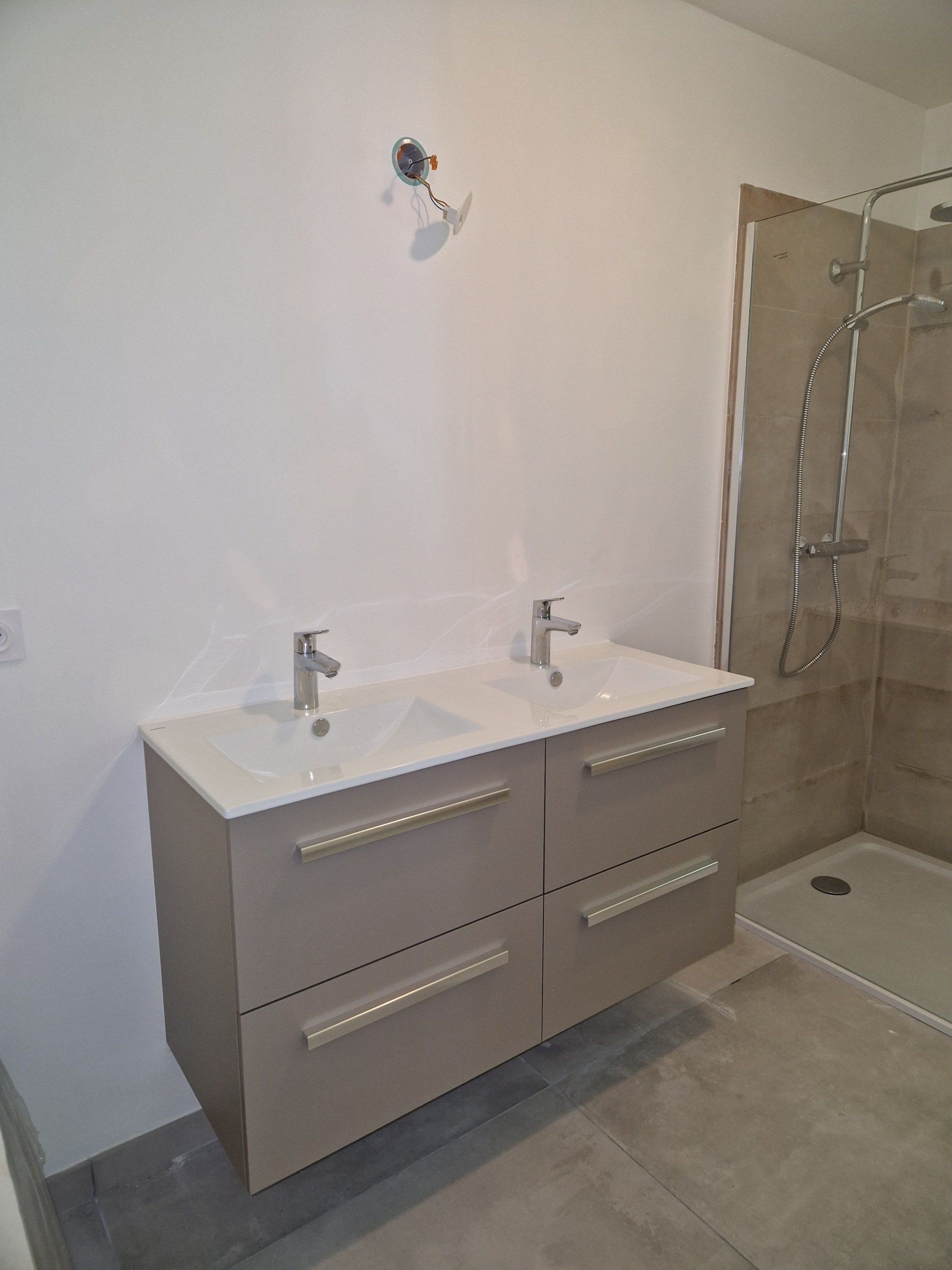 Deux lavabos blancs sur un meuble de salle de bains et une douche à l'italienne