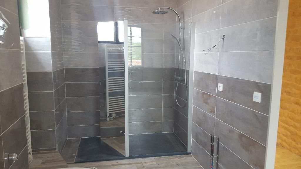 Douche à l'italienne dans une salle de bains grise avec un un sèche-serviettes