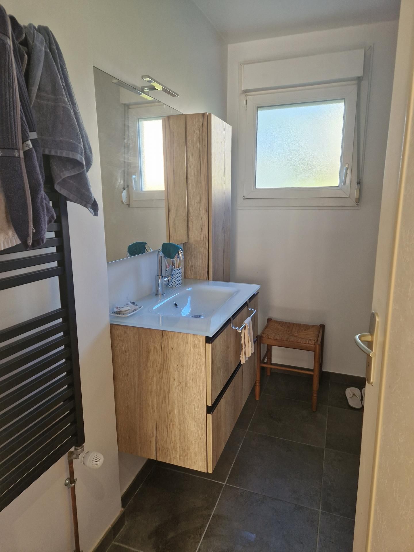Salle de bains rénovée avec des meubles en bois, un lavabo, un miroir et un un sèche-serviettes