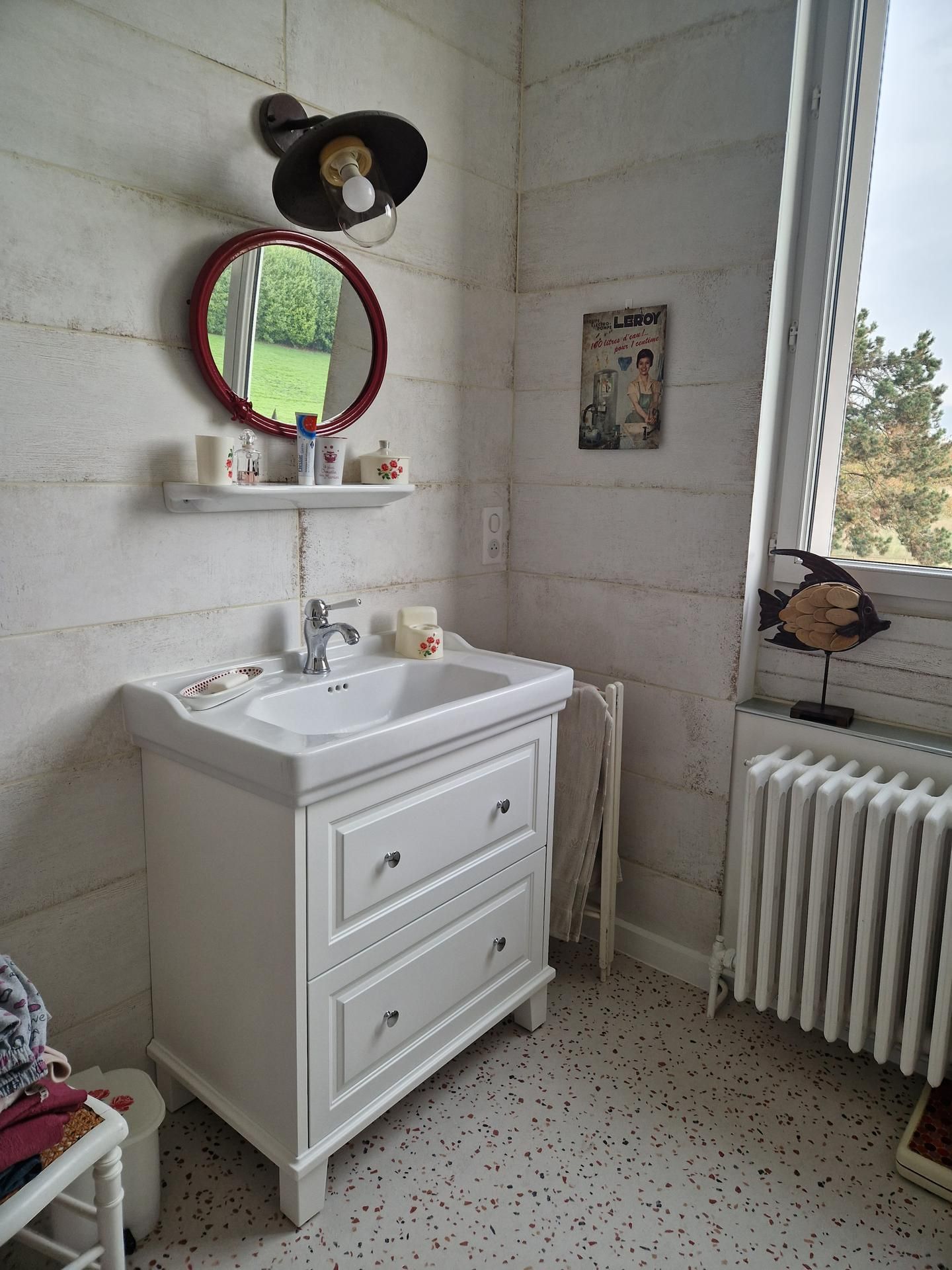 Salle de bains rénovée avec un lavabo sur un meuble blanc, un radiateur et des murs en pierre blanche