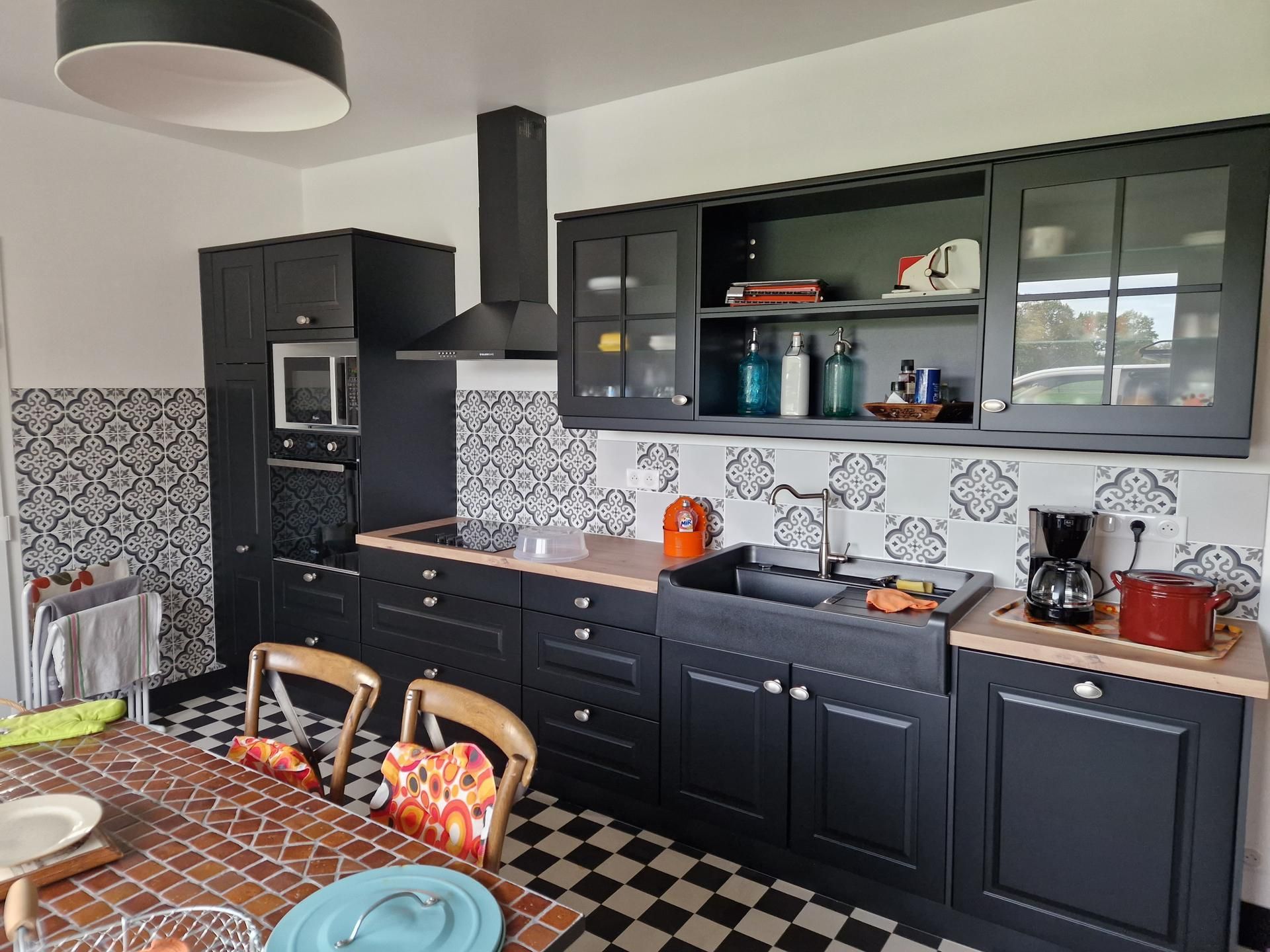 Cuisine équipée avec des placards noirs, une table et des chaises en façe