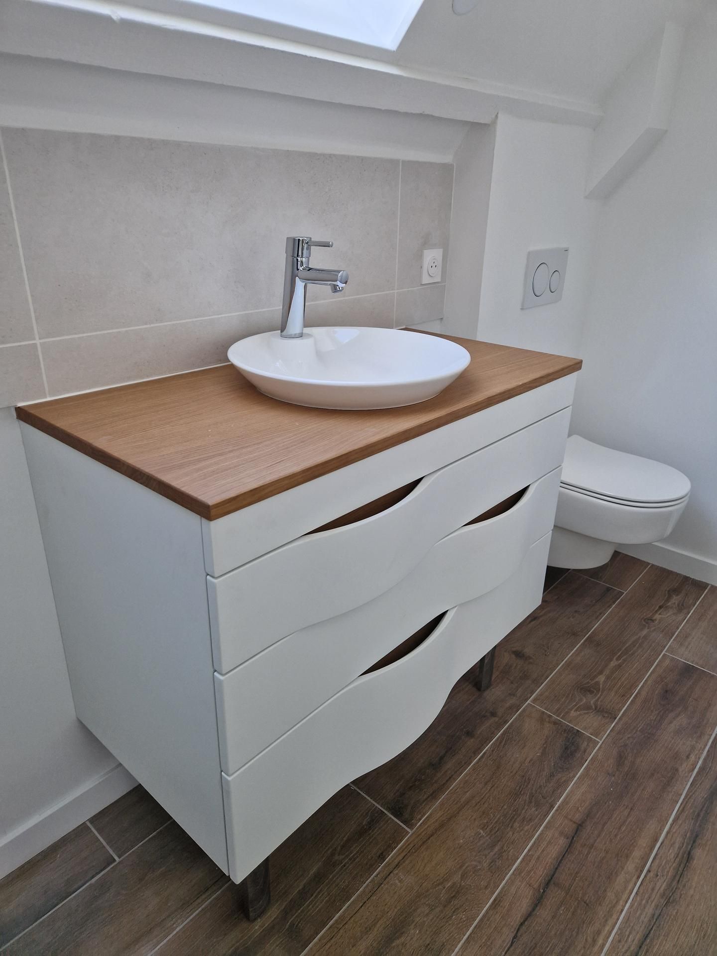 Vasque blanche sur un meuble de salle de bains et des toilettes à gauche