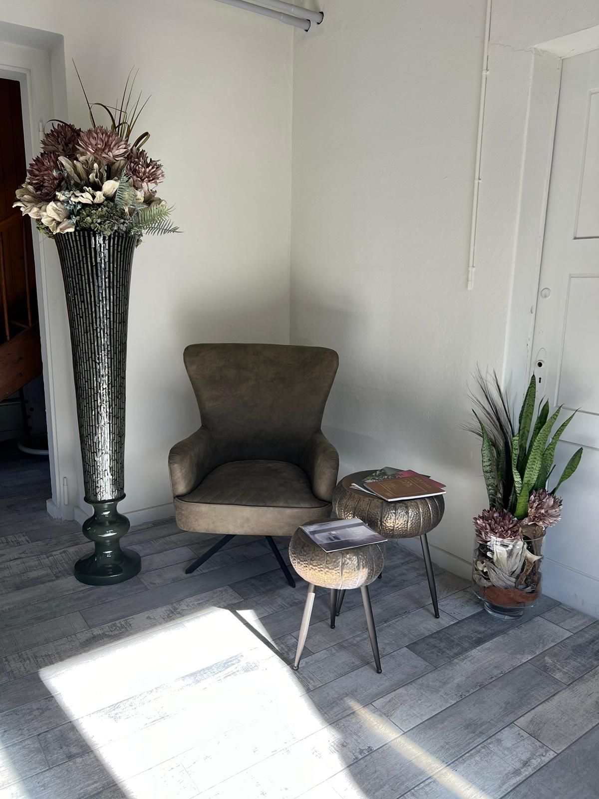 Ein Zimmer mit einem Stuhl, einem Tisch und einer Blumenvase.