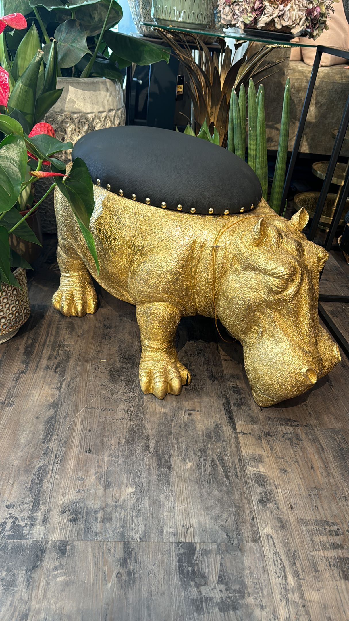 Auf einem Holzboden steht ein goldener Nilpferdhocker.