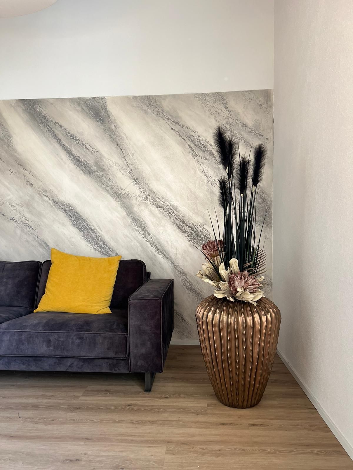 Ein Wohnzimmer mit einem Sofa und einer Vase mit Blumen.