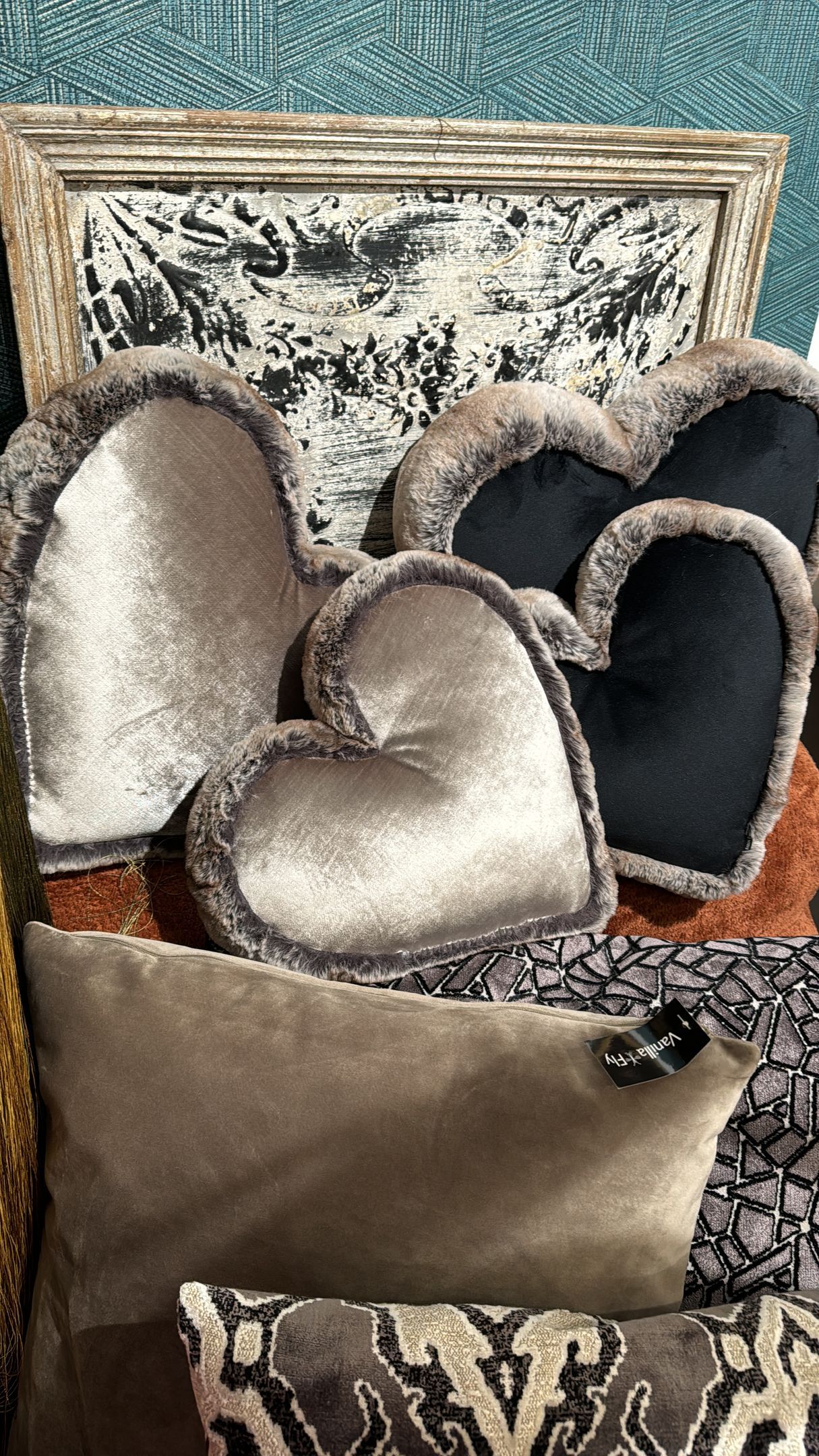 Auf einem Bett liegen mehrere herzförmige Kissen übereinander.