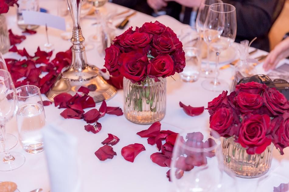 Ein Tisch mit roten Rosen und Rosenblättern darauf