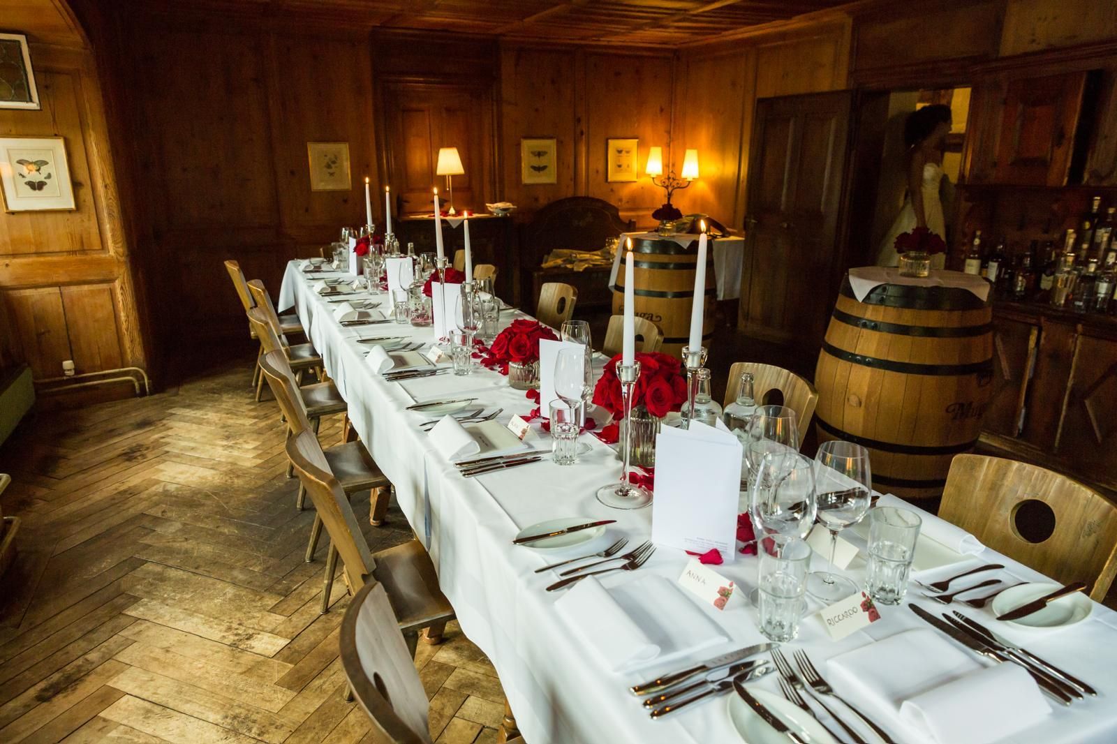 In einem Holzraum ist ein langer Tisch für eine Dinnerparty gedeckt.