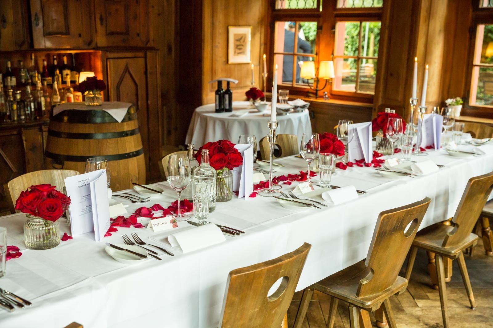Ein langer Tisch mit einer weißen Tischdecke und roten Rosen darauf