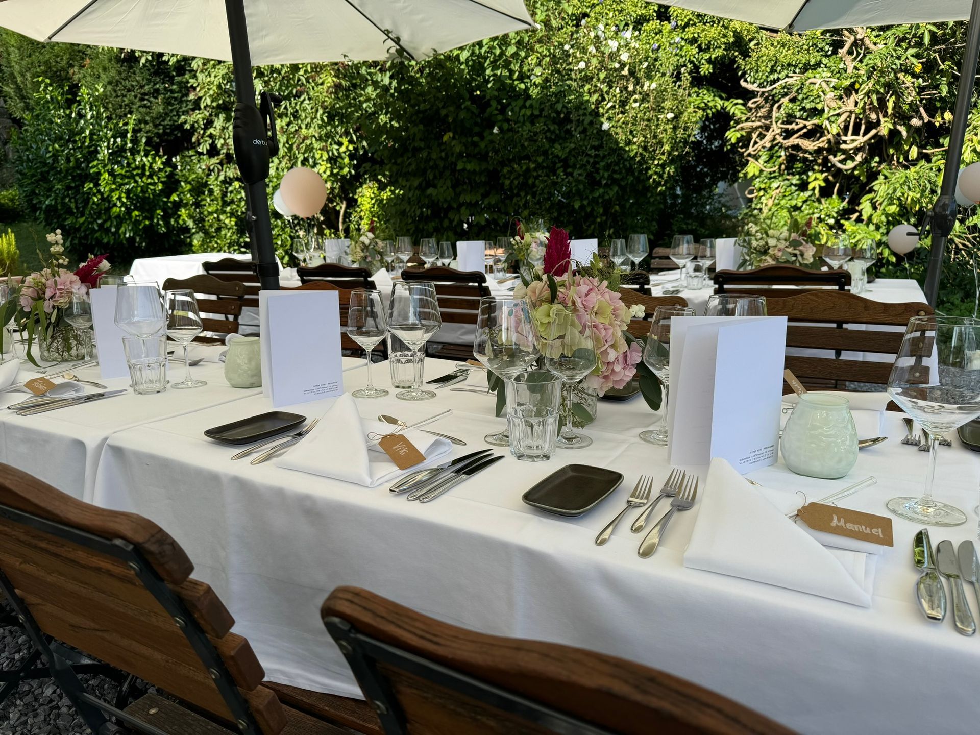 Ein langer Tisch mit Sonnenschirmen und Blumen darauf